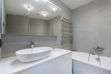 A bright bathroom with a mirrored cabinet over a bowl-sink with a white pedestal.