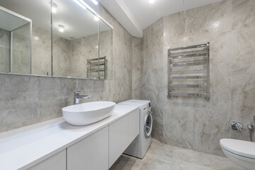 The interior of a modern bathroom in light gray tones with a large white cabinet, a sink-bowl and a mirrored cabinet.