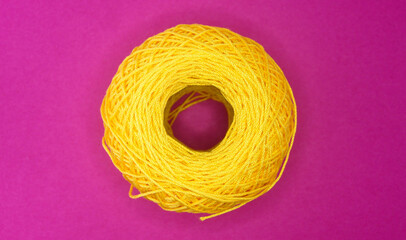 A spool of yellow thread close-up on a plain background, detailing, needlework, sewing, hobby