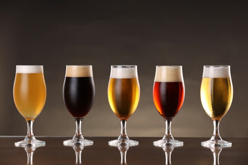 Glasses with different types of beer on mirror surface