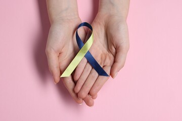 Woman with yellow and blue ribbon on pink background, top view. Down syndrome awareness