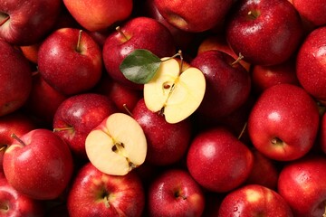 Fresh ripe red apples and green leaves as background, top view