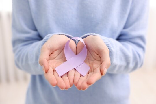 Woman with violet ribbon on light background, closeup. Alzheimer disease, epilepsy and pancreas cancer awareness