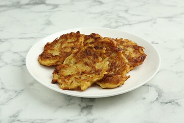 Delicious potato pancakes on white marble table, closeup