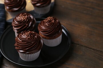 Tasty cupcakes with chocolate cream on wooden table, space for text
