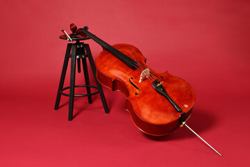 Beautiful cello and stool on red background. Classic musical instrument