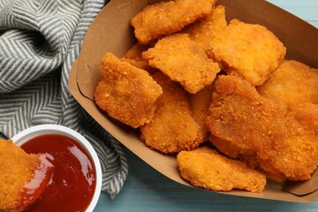 Delicious chicken nuggets with ketchup on blue wooden table, flat lay