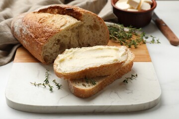 Fresh bread with butter and thyme on white table, closeup