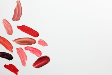 Smears of different lip products on white background, top view