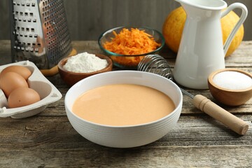Bowl with dough and ingredients for pumpkin pancakes on wooden table