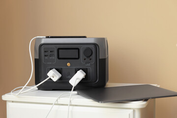 Devices charging from portable power station on nightstand indoors