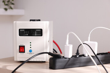 Portable power station and multi-socket extension board with chargers on table indoors