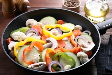 Frying pan with mix of vegetables and mushrooms on wooden table, closeup