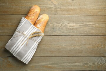 Fresh baguettes and spikes on wooden table, top view. Space for text
