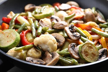 Different vegetables and mushrooms in frying pan, closeup