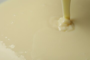 Pouring delicious condensed milk as background, closeup