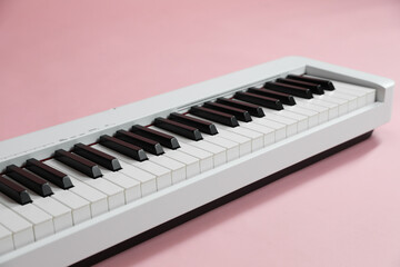 Synthesizer on pink background, closeup. Electronic musical instrument