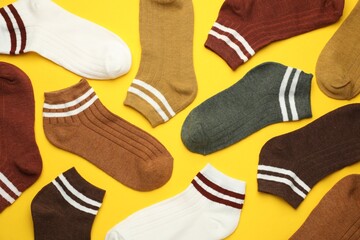 Different soft socks on yellow background, flat lay