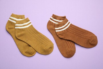 Different soft socks on violet background, flat lay