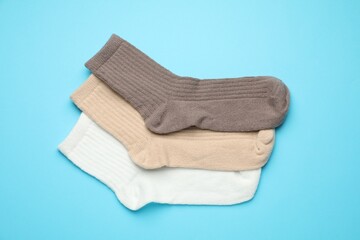 Different soft socks on light blue background, flat lay