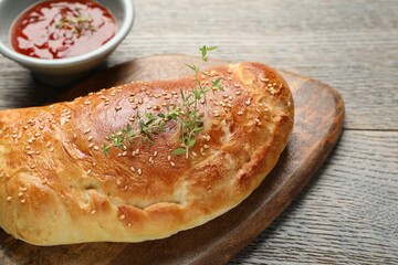 Delicious fresh calzone pizza served on wooden table, closeup