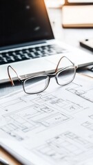  foreground of objects on the working place: eyeglasses, diagrammes, laptop, notebook