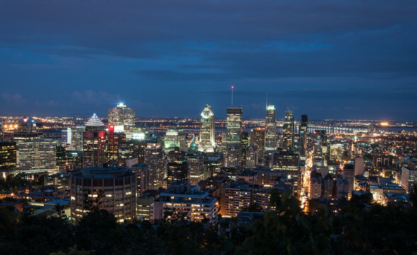 Stunning nighttime view of downtown Montreal, Canada, with illuminated skyscrapers and vibrant city lights under a deep blue sky. Perfect for urban and travel themes.