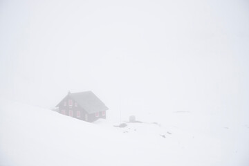 Mountain hut in fog and snow