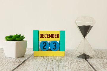 Cube shape calendar for December 23 on wooden surface with empty space for text