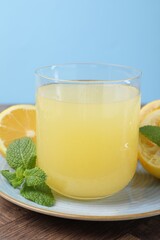 Glass of lemon juice and fresh fruits on wooden table, closeup
