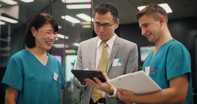 Clinic, nurses or health manager with tablet in meeting for staff management or healthcare service delivery. Medical admin, mature person or team with digital checklist for hospital schedule in Japan