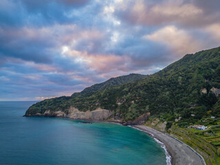 Fototapeta premium Aerial drone view of Praia do Fogo with volcanic black sand beach in Ribeira Quente. Landscape of Sao Miguel coastline with green mountains in Azores
