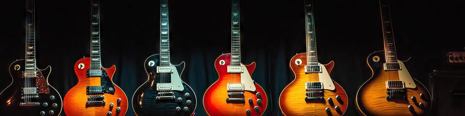 Fototapeta premium Rock: A row of simple electric guitars, bass, and drums on a dimly lit stage
