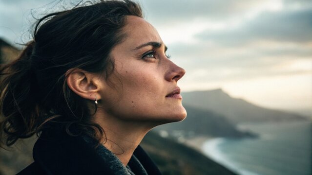 A woman staring off into the distance her expression contemplative and distant. Striking highlights on her cheekbones juxtapose with dark shadows beneath her chin reflecting the