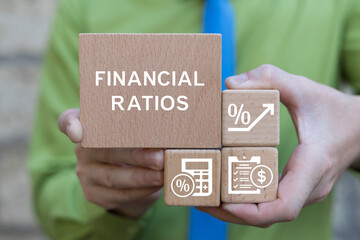 Business man holding wooden blocks sees text: FINANCIAL RATIOS. Financial Ratio Analysis Business...