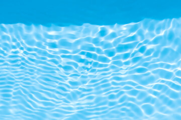 Blue water with ripples on the surface. Defocus blurred transparent blue colored clear calm water surface texture with splashes and bubbles. Water waves with shining pattern texture background.
