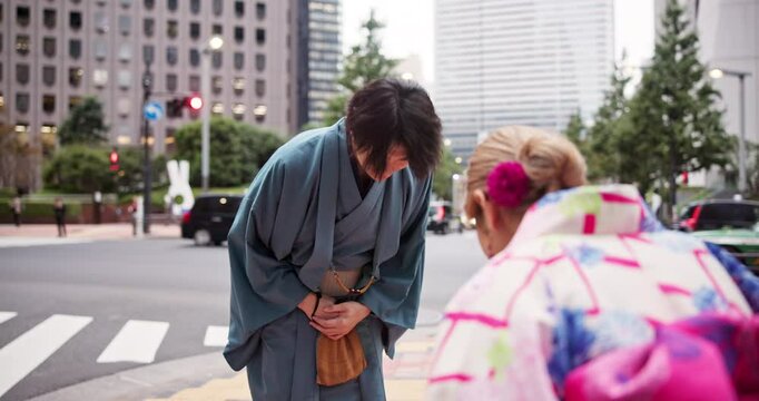 Bow, respect and japanese people in city with greeting, culture and tradition with kimono. Outdoor, urban and Tokyo street with kowtow and heritage custom with Asian robe in town with local clothes