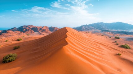 An aerial shot of a vast desert landscape, with wind sculpted sand dunes forming natural triangular patterns.