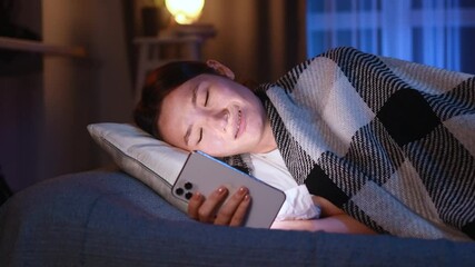 Portrait of crying young asian woman with smartphone under the blanket and reading bad news email break up message from ex-boyfriend or personal problems at home at late night
