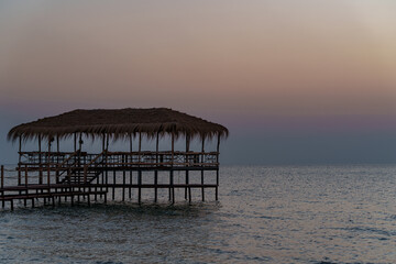 Obraz premium A beautiful view of the sunrise, sunset over the sea horizon with a pier in the foreground