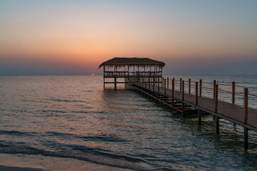 Fototapeta premium A beautiful view of the sunrise, sunset over the sea horizon with a pier in the foreground