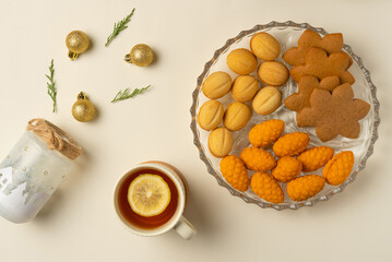 Plate with cookies, cup of tea and decoration on beige background. Flat lay, top view.