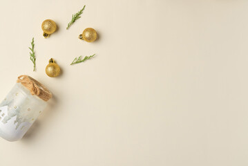Christmas trinkets spill out of handmade jar on beige background. Flat lay, top view. Copy space
