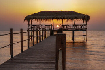 Fototapeta premium A beautiful view of the sunrise, sunset over the sea horizon with a pier in the foreground