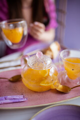 Tea in a teapot with orange and sea buckthorn in a glass bowl on a white table in a cafe.