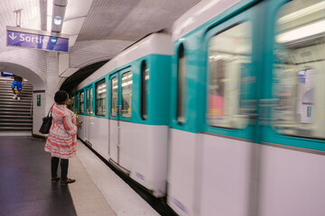 Subway of Paris, France. Woman waiting for the subway. Sortie blue sign.