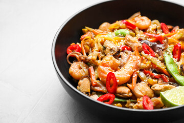 Stir-fry sea food in bowl on light grey table, closeup