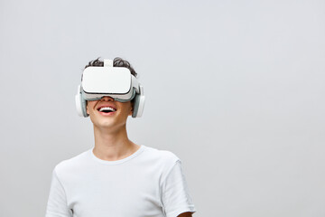 Virtual reality experience, smiling young man with VR headset, light gray background, engaging with technology, modern lifestyle, innovation in entertainment and gaming