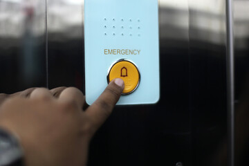 Close up of a hand pressing the emergency button in an elevator