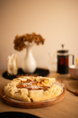 Freshly baked pear biscuit on a wooden table. Dried hydrangea in a white vase. Teapot with tea.